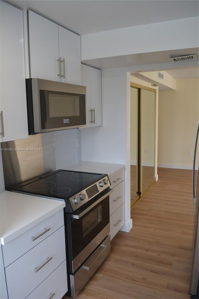 kitchen featuring white cabinetry, light hardwood / wood-style flooring, stainless steel appliances, and tasteful backsplash