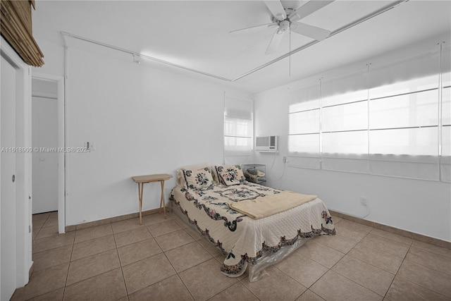 bedroom with light tile patterned floors, a wall unit AC, and ceiling fan