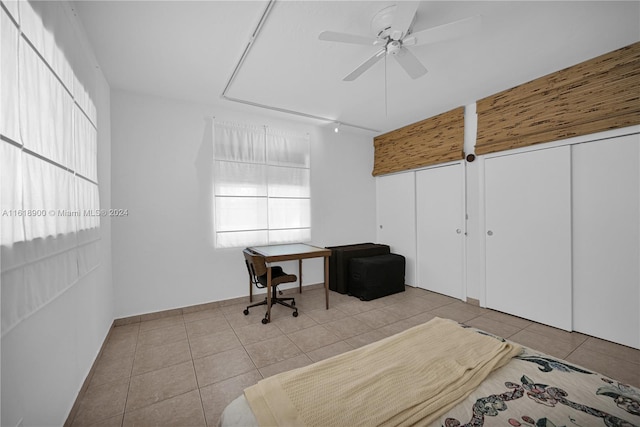 tiled bedroom featuring ceiling fan and a closet