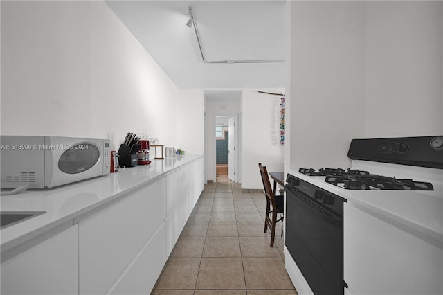 kitchen with white cabinetry, white appliances, and light tile patterned floors