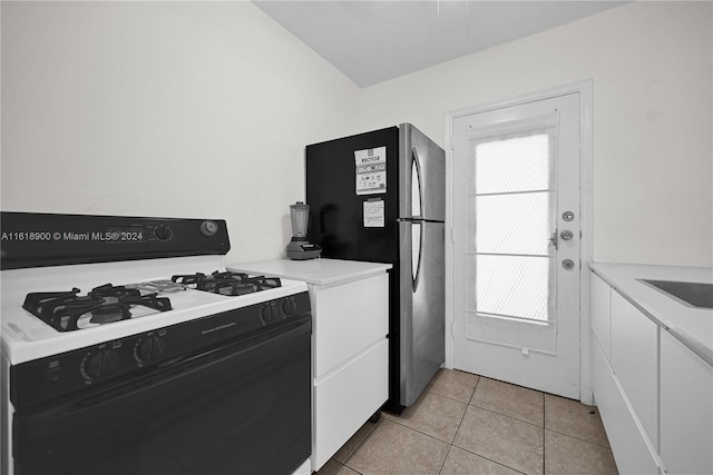 kitchen with white cabinetry, white gas range, stainless steel refrigerator, and light tile patterned flooring