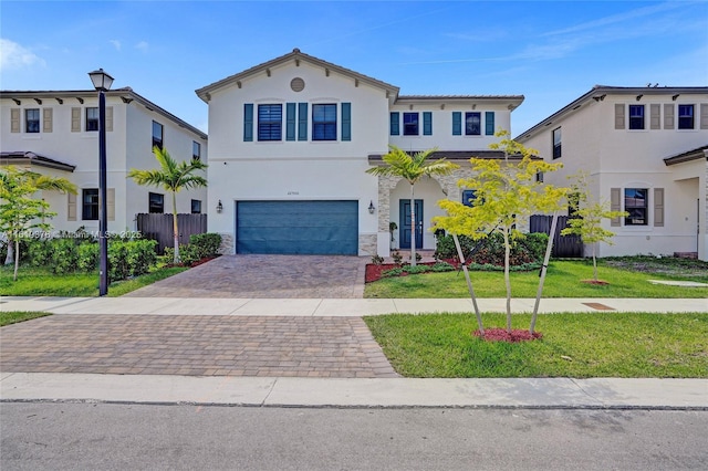 view of front facade with a garage, fence, decorative driveway, stucco siding, and a front lawn