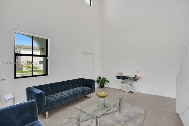 living room featuring tile patterned flooring, a towering ceiling, and baseboards