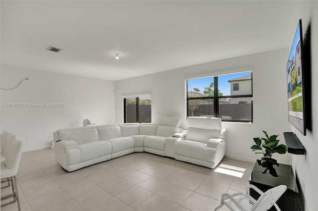 living room with light tile patterned floors, visible vents, and baseboards