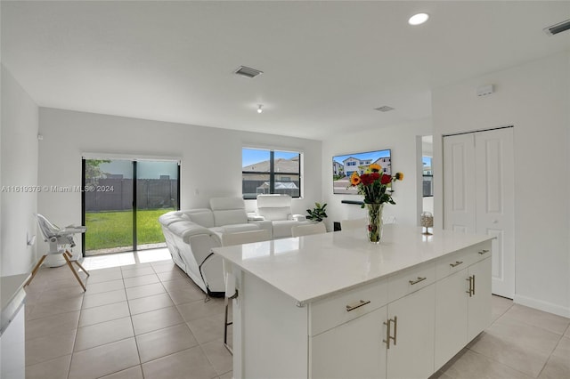 kitchen with a breakfast bar, white cabinetry, light tile patterned floors, and a center island