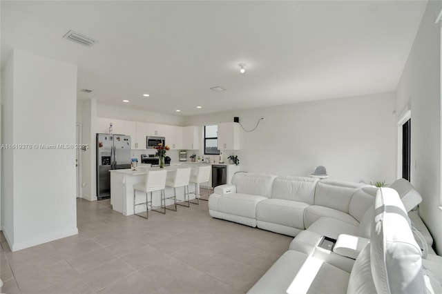 living area featuring recessed lighting, visible vents, and baseboards