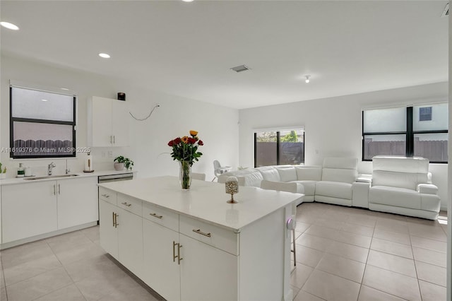 kitchen with a kitchen island, visible vents, a sink, and light tile patterned floors