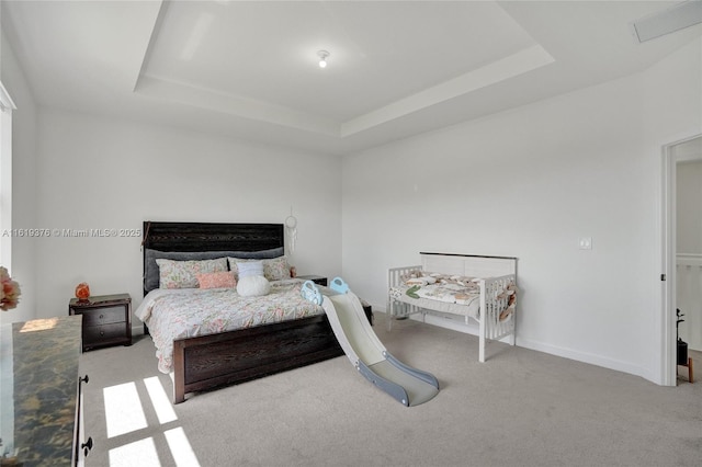 bedroom with a tray ceiling, baseboards, visible vents, and carpet flooring