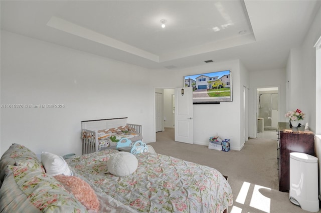 bedroom with a tray ceiling, light carpet, visible vents, and baseboards