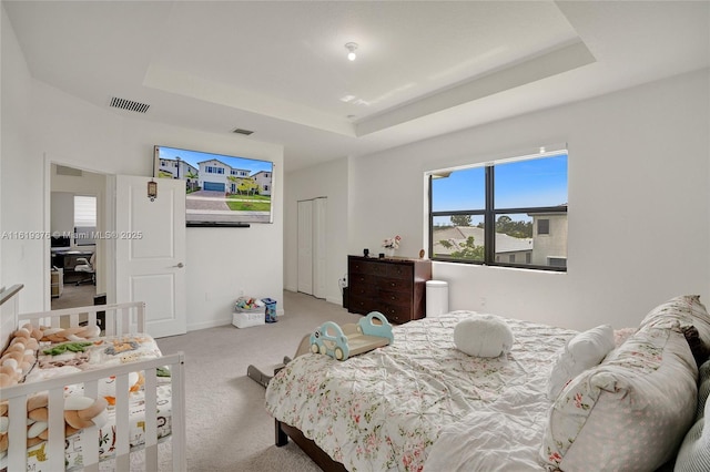 bedroom featuring a tray ceiling, visible vents, and carpet flooring