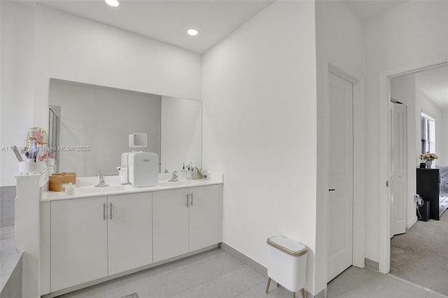 bathroom with baseboards, double vanity, a sink, and recessed lighting