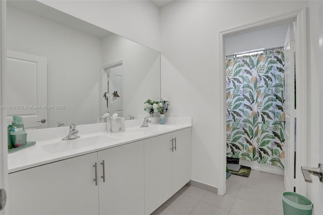 bathroom with double vanity, tile patterned floors, a sink, and baseboards