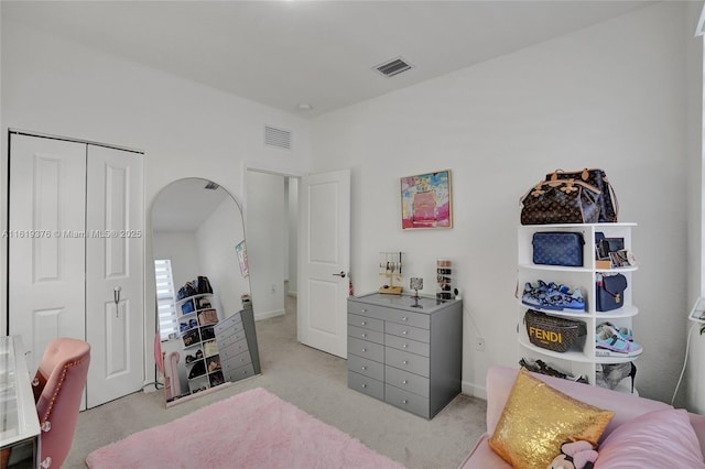 bedroom featuring visible vents, arched walkways, a closet, and light colored carpet