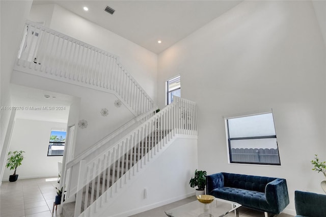 staircase featuring a towering ceiling and tile patterned flooring