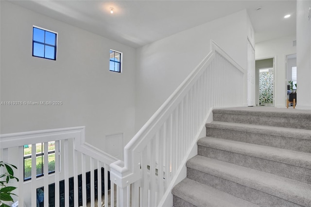 stairs featuring recessed lighting, a decorative wall, and a towering ceiling