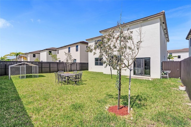 rear view of property featuring a fenced backyard, a lawn, and stucco siding