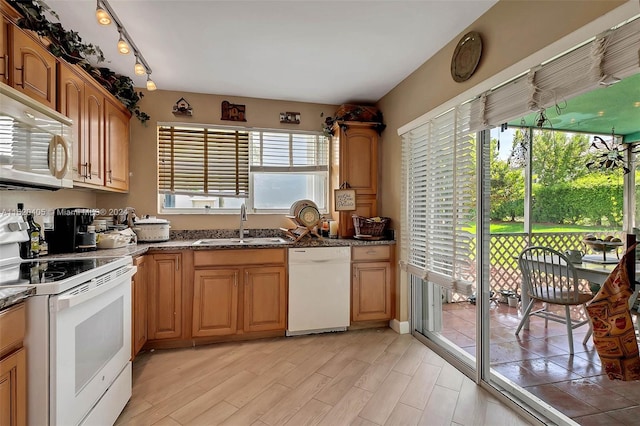 kitchen featuring white appliances, light hardwood / wood-style flooring, dark stone countertops, and sink