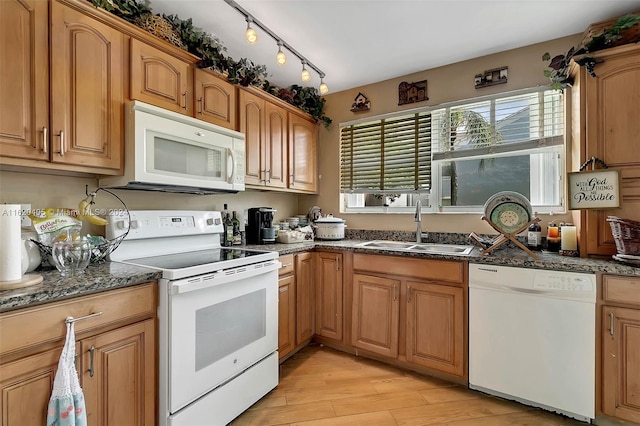 kitchen with white appliances, sink, dark stone counters, and light hardwood / wood-style flooring