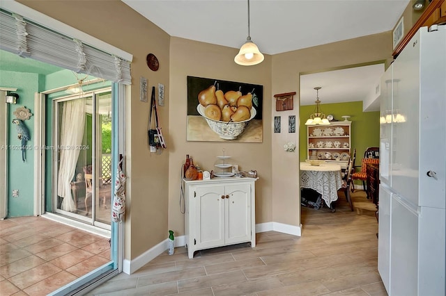 interior space with a chandelier, light hardwood / wood-style floors, white cabinetry, and hanging light fixtures