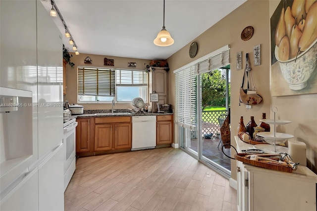 kitchen featuring pendant lighting, white appliances, sink, and light hardwood / wood-style flooring