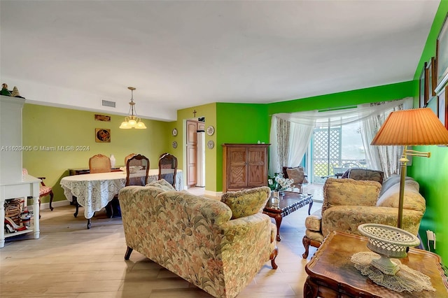 living room with light hardwood / wood-style floors and a notable chandelier