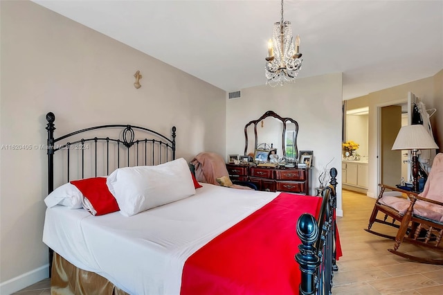 bedroom with ensuite bathroom, light hardwood / wood-style flooring, and a notable chandelier