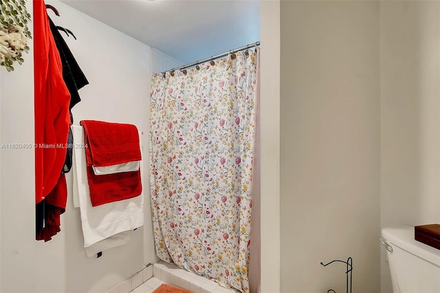 bathroom with toilet and a shower with shower curtain