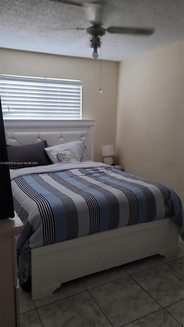 bedroom featuring tile patterned flooring, a textured ceiling, and ceiling fan