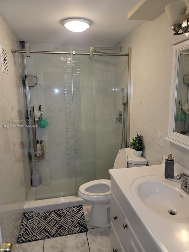 bathroom featuring tile walls, walk in shower, tile patterned floors, toilet, and vanity