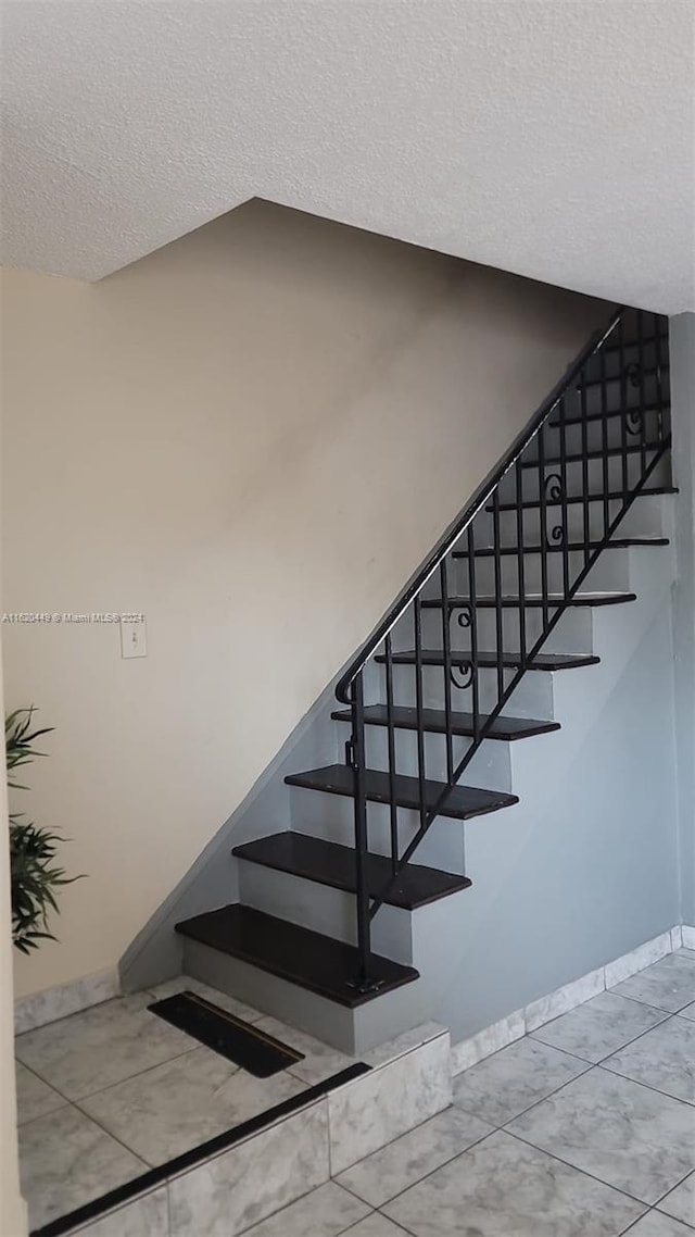 stairway with tile patterned floors and a textured ceiling