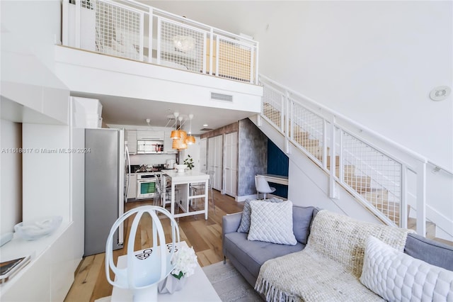 living room with a towering ceiling and light hardwood / wood-style flooring