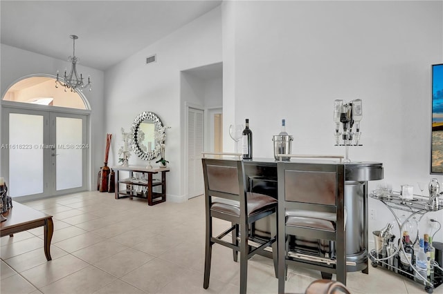 interior space featuring french doors, vaulted ceiling, hanging light fixtures, and light tile patterned flooring