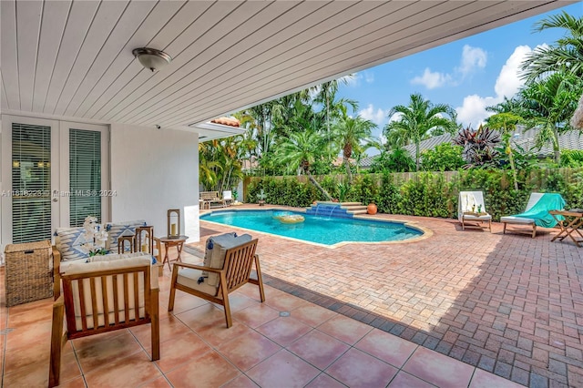 view of swimming pool with outdoor lounge area, french doors, pool water feature, and a patio area