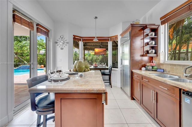 kitchen featuring decorative light fixtures, a kitchen island, light tile patterned floors, and stainless steel appliances