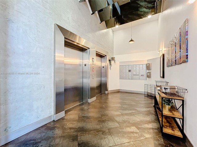 hall featuring elevator, tile patterned floors, and a towering ceiling