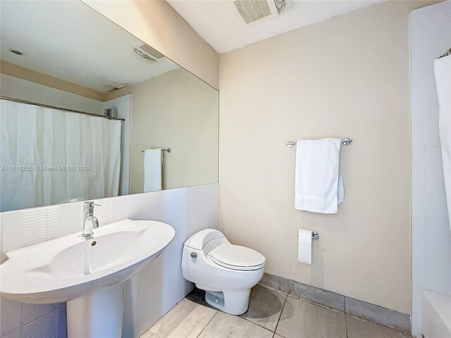 full bathroom featuring sink, toilet, tile patterned flooring, and shower / bath combination with curtain