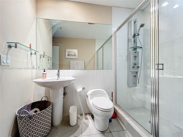 bathroom with a shower with shower door, tile patterned flooring, and toilet