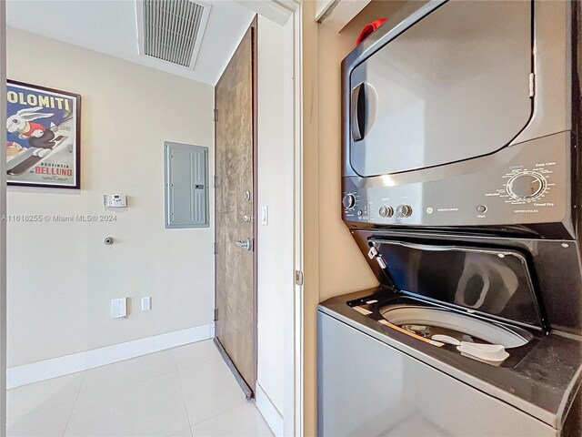 washroom featuring stacked washer and dryer, light tile patterned flooring, and electric panel