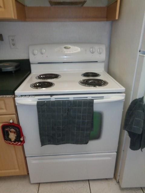 kitchen with white electric stove and light tile patterned floors