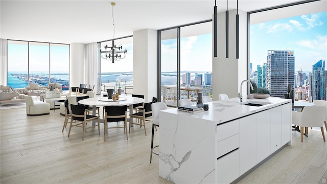 dining room featuring a water view, light hardwood / wood-style floors, a chandelier, expansive windows, and sink