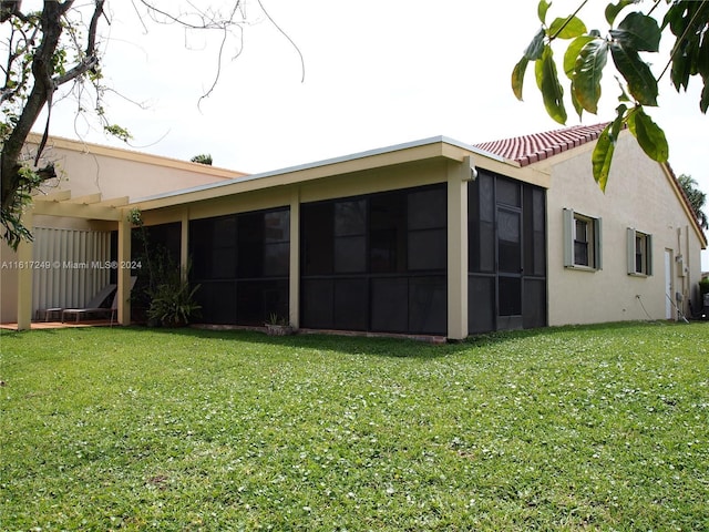 rear view of house featuring a sunroom and a yard