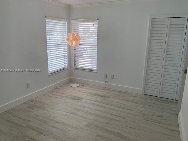 unfurnished bedroom with light wood-type flooring, a closet, and crown molding