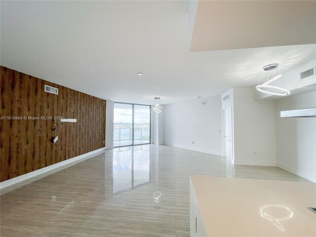 unfurnished living room featuring wood walls and a wall of windows