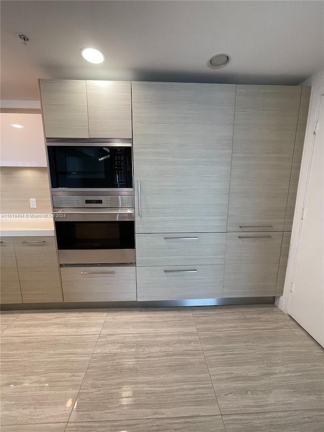 kitchen featuring modern cabinets, built in microwave, light countertops, and oven