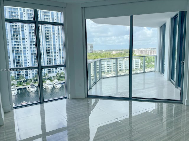 unfurnished room featuring a wall of windows, a water view, tile patterned flooring, and a city view