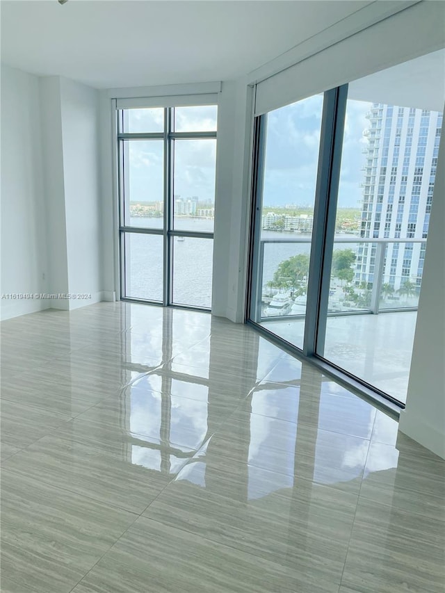 empty room with a wealth of natural light, expansive windows, and a water view