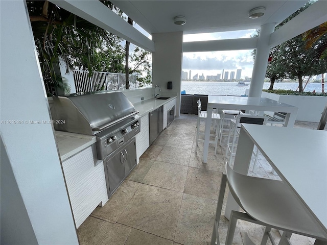 view of patio with a view of city, a water view, a sink, and area for grilling