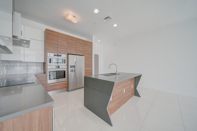 kitchen featuring a kitchen island with sink, light tile patterned floors, appliances with stainless steel finishes, and sink