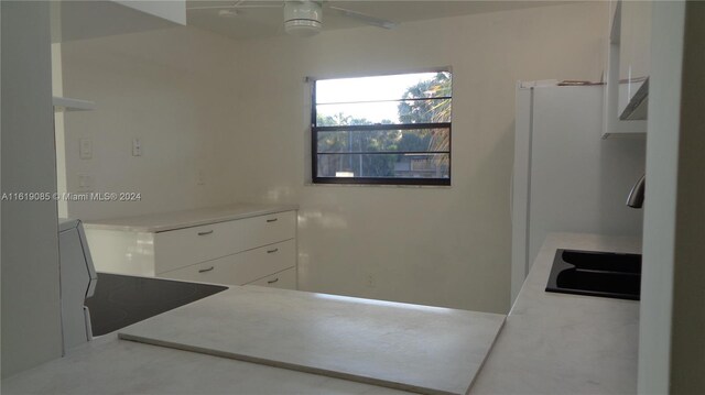 kitchen featuring concrete floors, white cabinetry, and ceiling fan