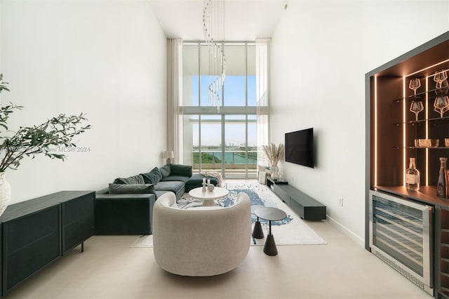 living room with baseboards, wine cooler, expansive windows, a high ceiling, and a bar